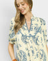 Woman wearing a yellow and blue patterned dress against a plain background