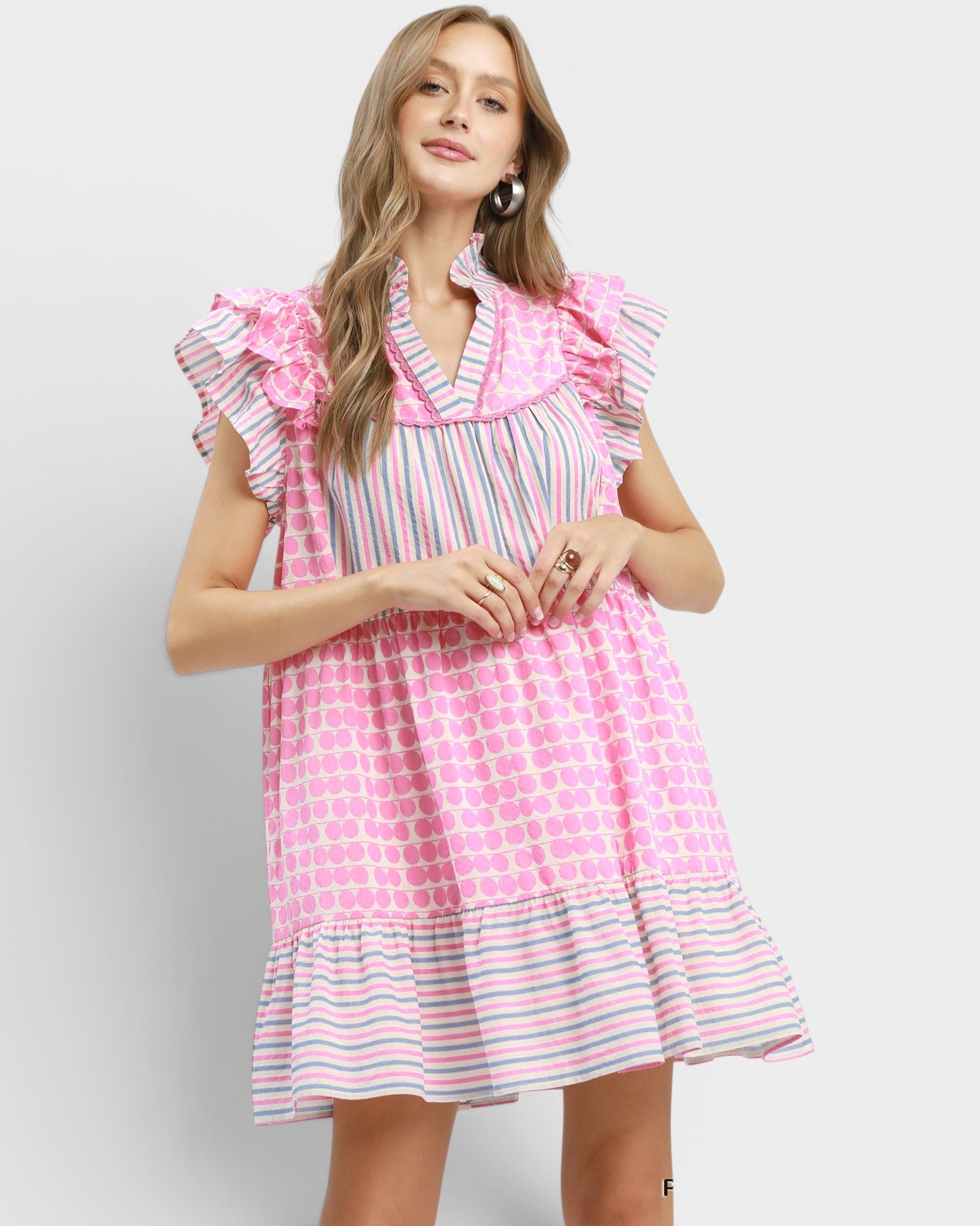 Woman wearing a pink and white checkered dress with ruffled sleeves on a light gray background
