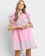 Woman wearing a pink and white checkered dress with ruffled sleeves on a light gray background