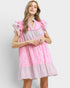 Woman wearing a pink and white checkered dress with ruffled sleeves on a light gray background