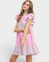 Woman wearing a pink and white checkered dress with ruffled sleeves on a white background