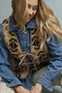 Woman wearing a leopard print vest over a denim shirt against a neutral background