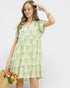 Woman wearing a green and white patterned dress on a plain background