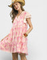 Woman wearing a pink and white patterned dress with a straw hat on a light gray background
