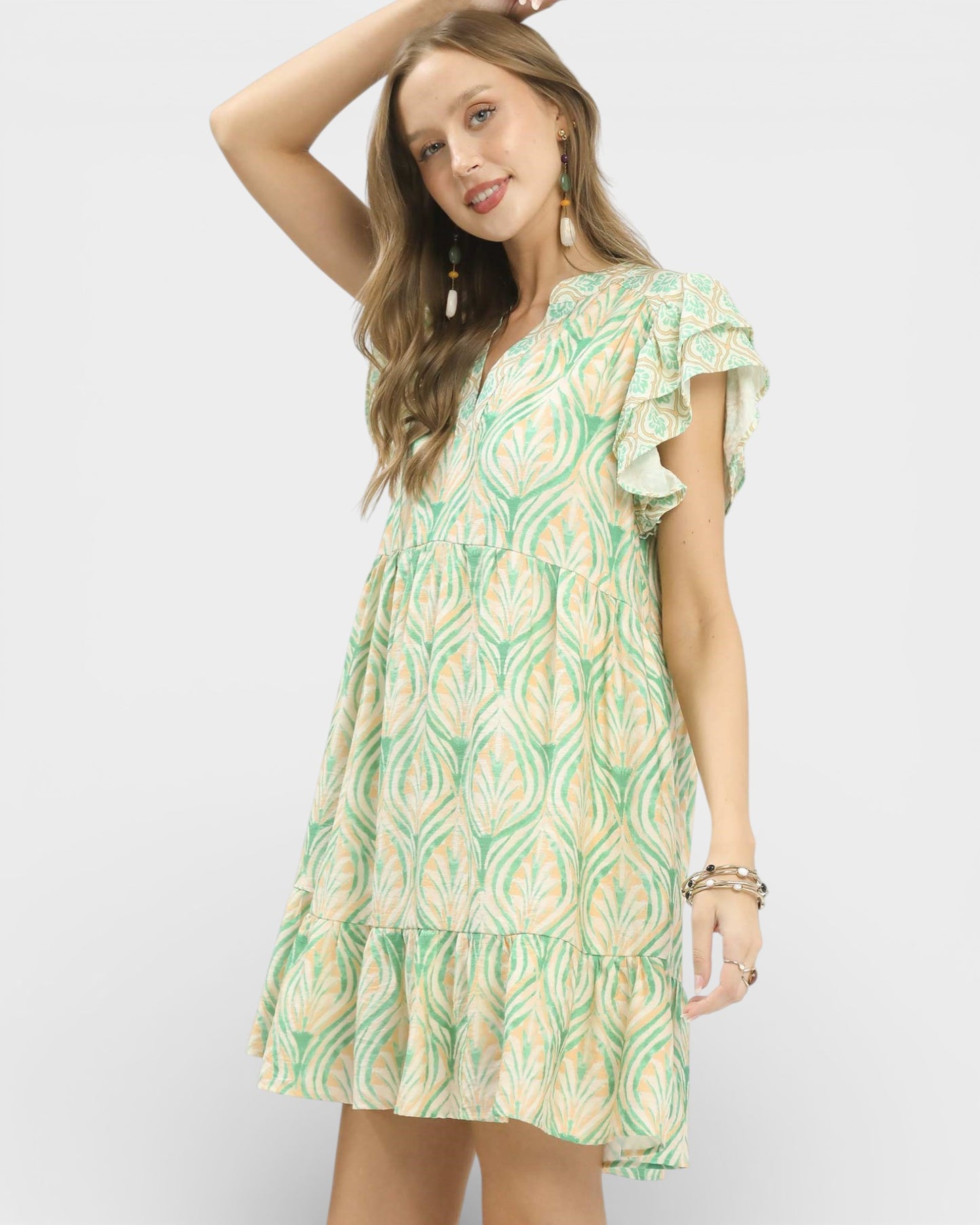 Woman wearing a green and white patterned dress on a plain background