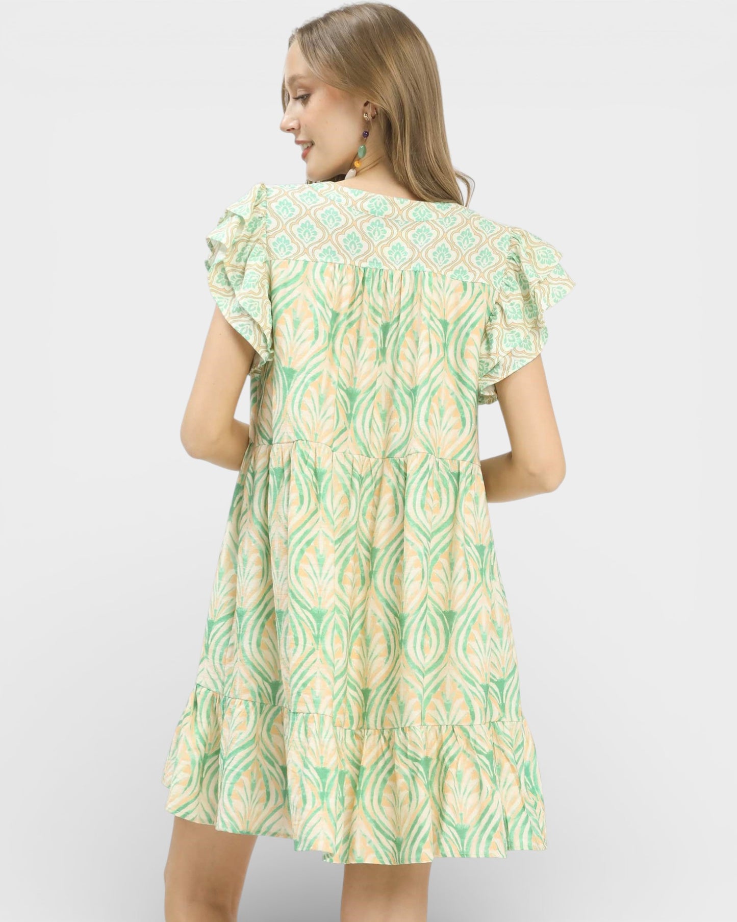 Woman wearing a green and white patterned dress on a white background