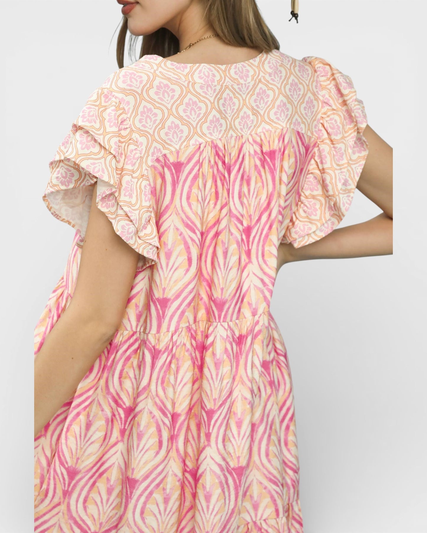 Woman wearing a pink and orange patterned dress on a white background