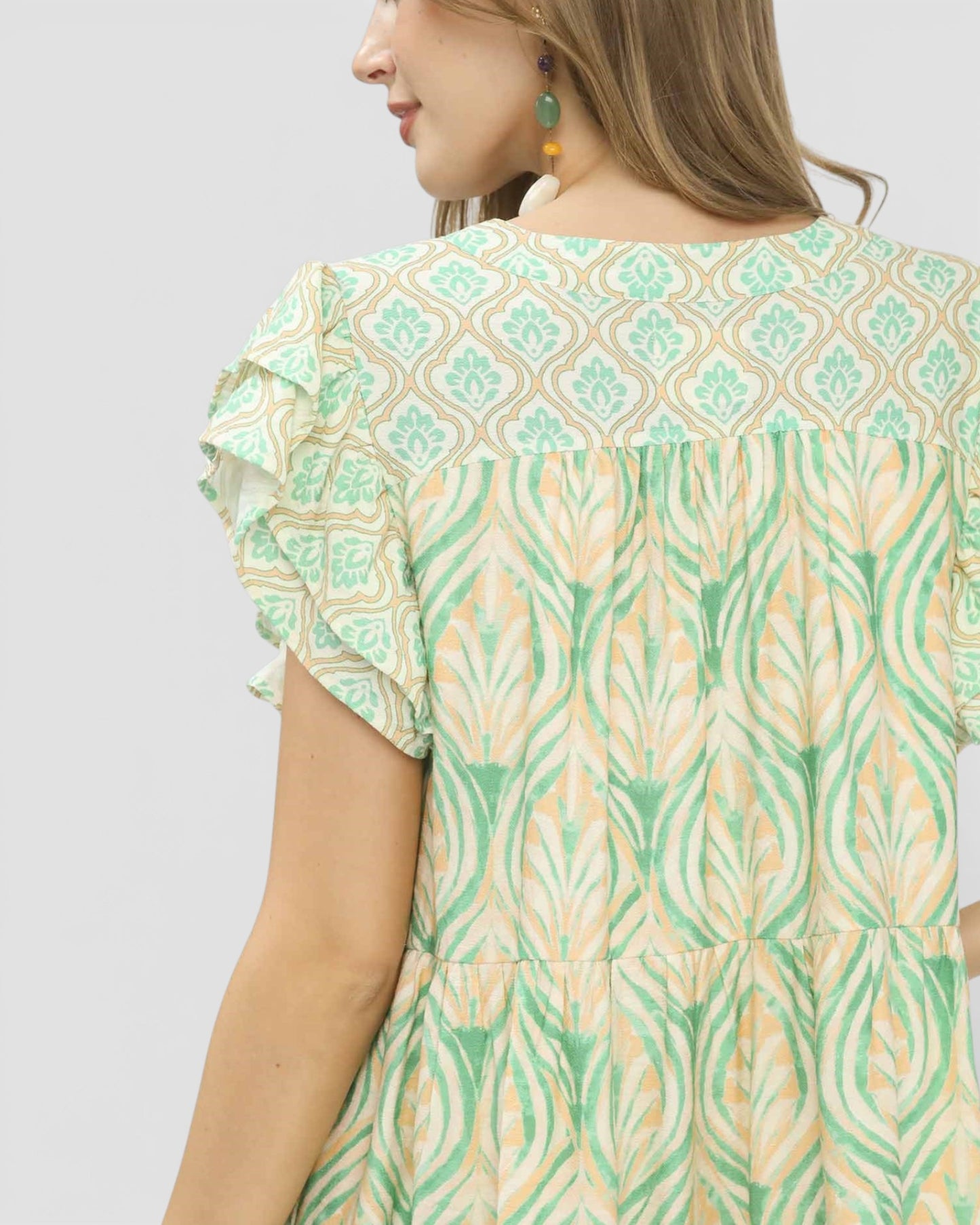 Woman wearing a green and beige patterned dress on a light gray background