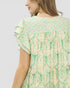 Woman wearing a green and beige patterned dress on a light gray background