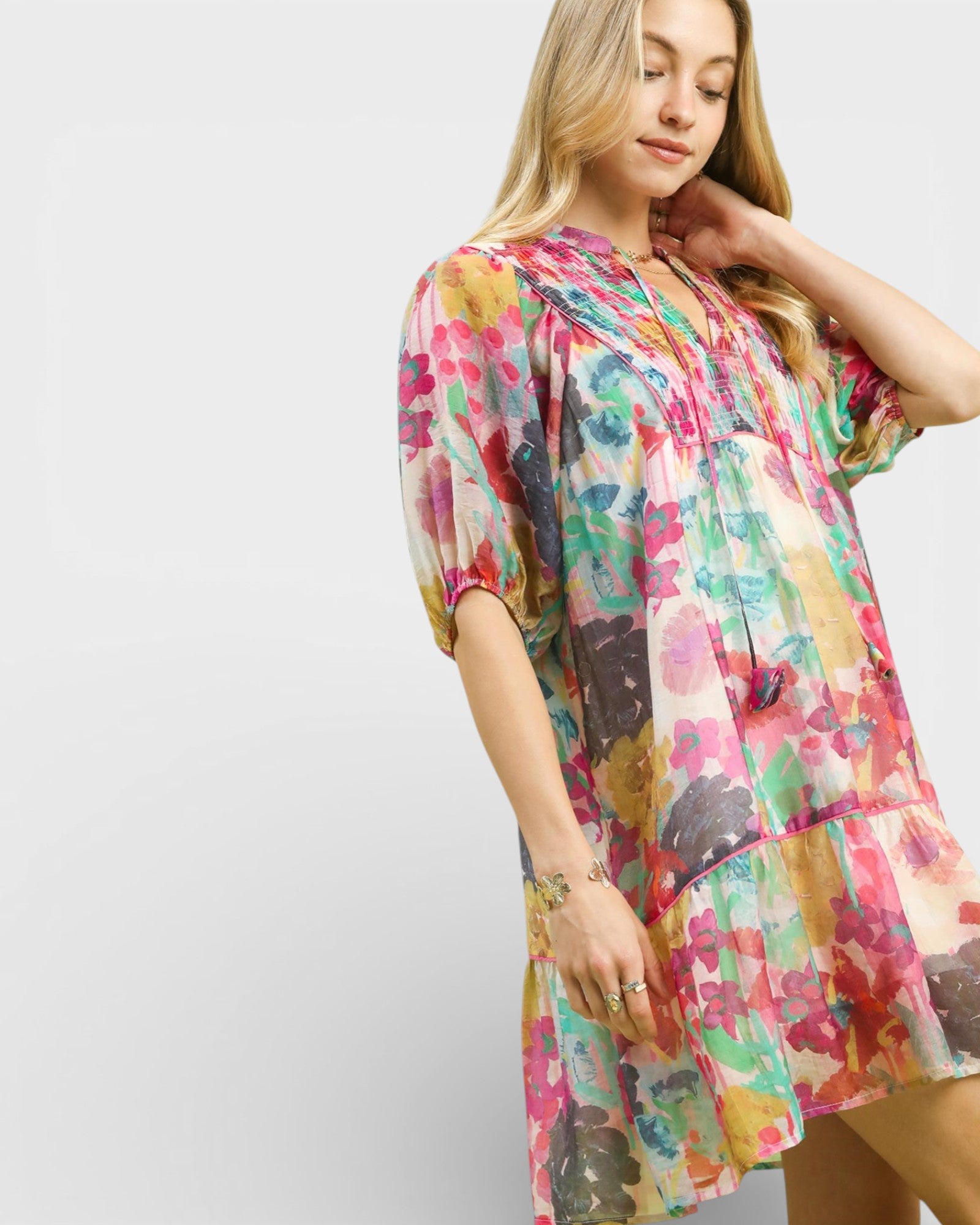 Woman wearing a colorful floral dress against a plain background