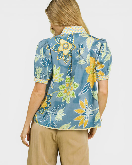 Woman wearing a blue floral shirt with a plain background