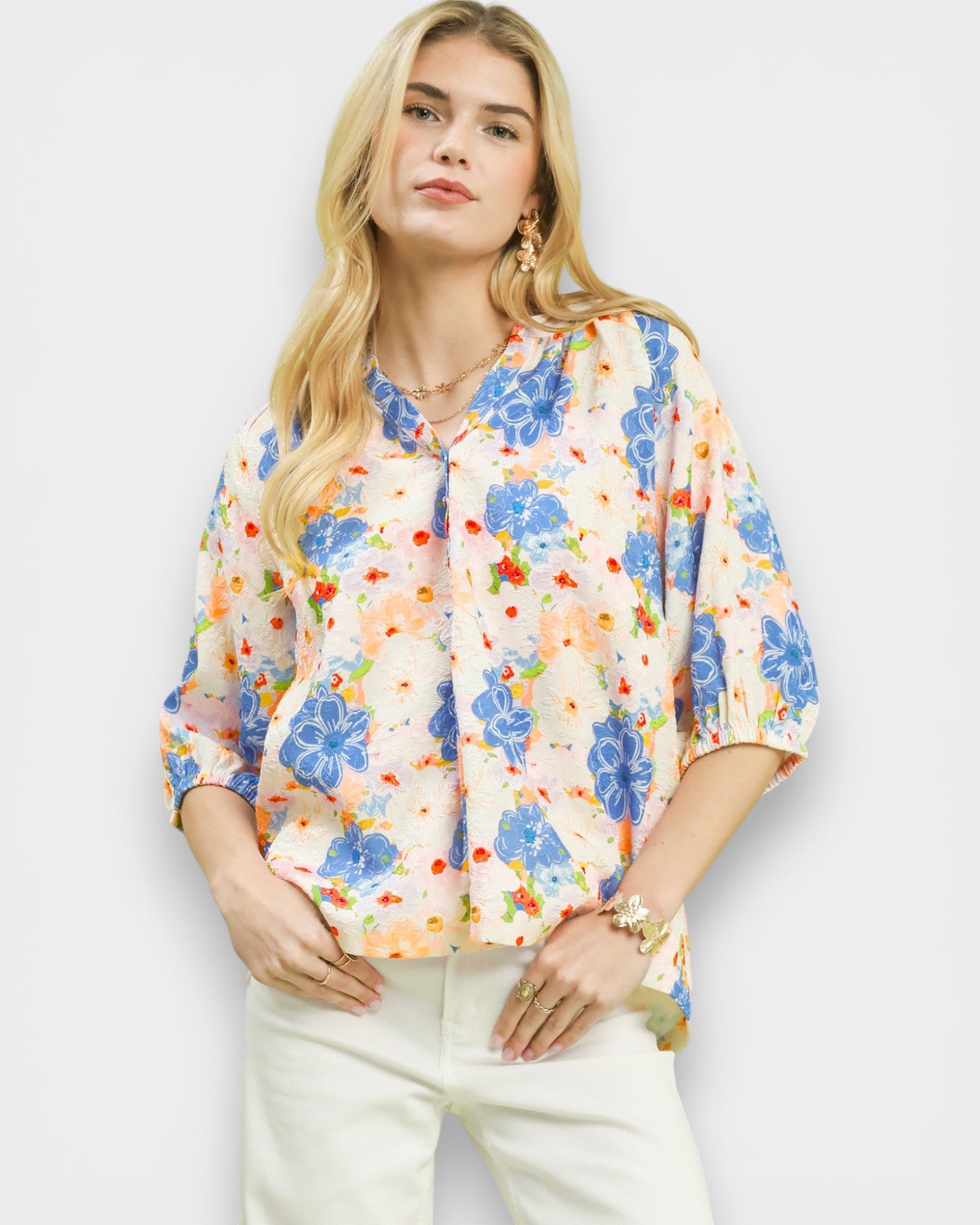 Woman wearing a colorful floral blouse against a white background