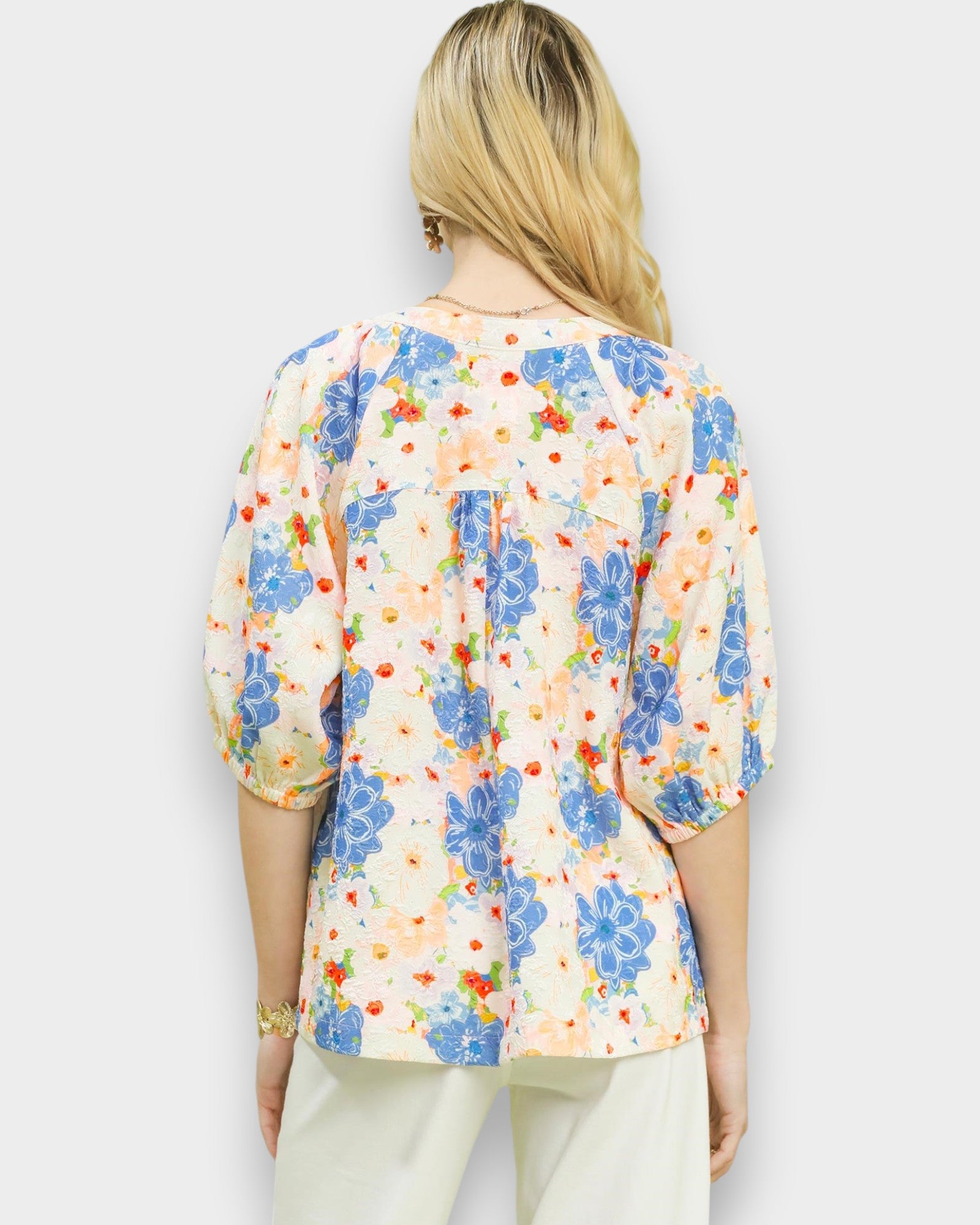 Woman wearing a colorful floral blouse against a white background