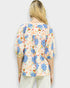 Woman wearing a colorful floral blouse against a white background