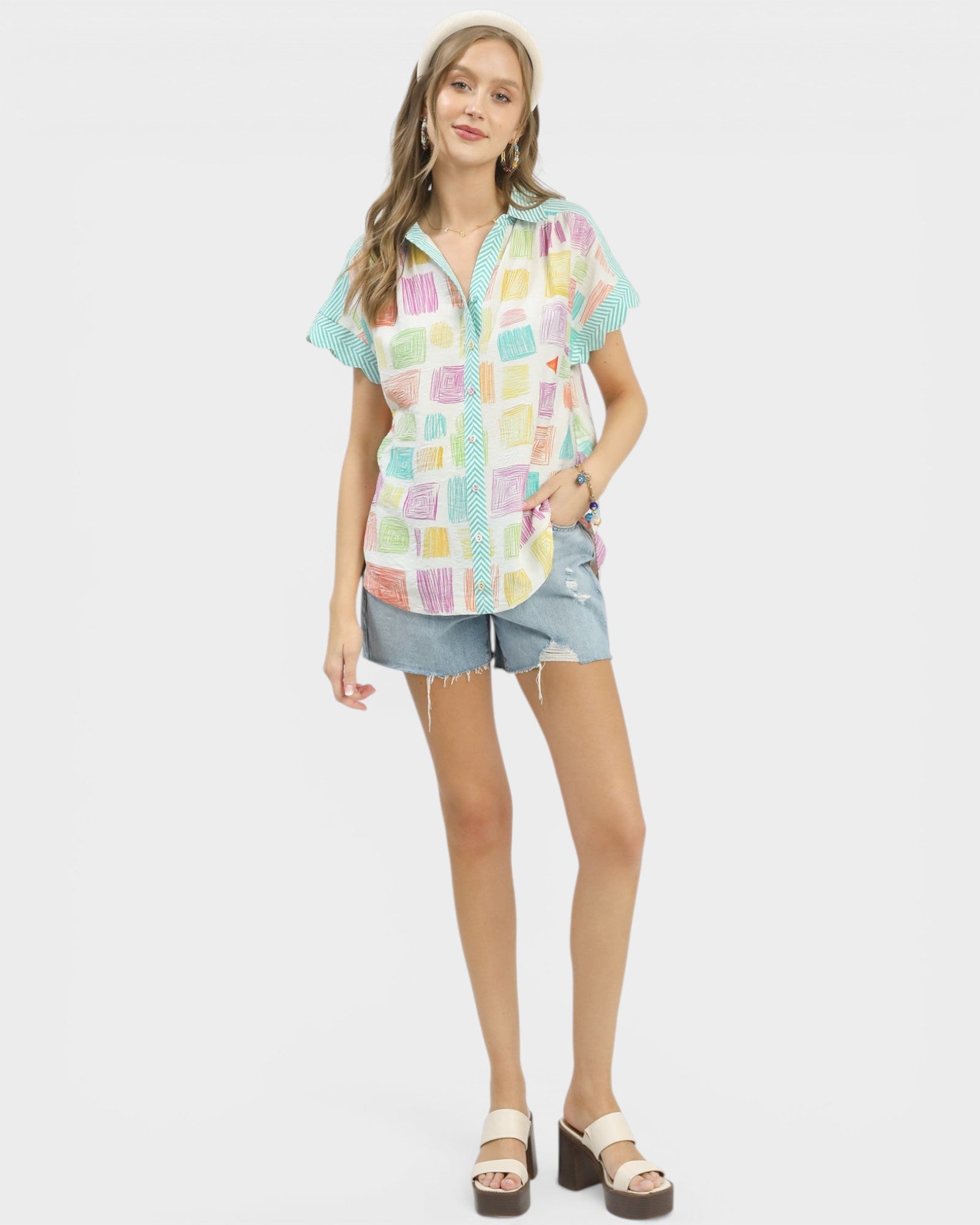 Woman wearing a colorful checkered shirt and denim shorts on a white background