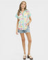 Woman wearing a colorful checkered shirt and denim shorts on a white background