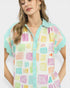 Woman wearing a colorful geometric patterned shirt on a white background