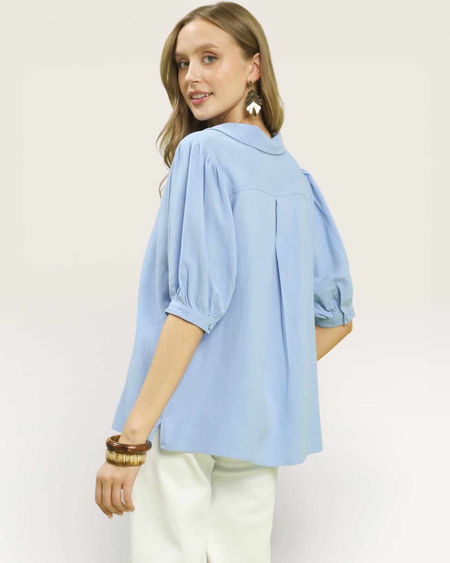 Woman wearing a light blue blouse with a plain background
