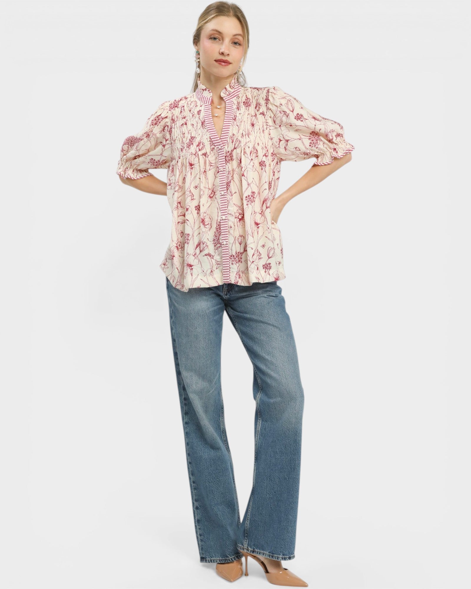 Woman wearing a floral blouse and blue jeans on a white background