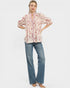 Woman wearing a floral blouse and blue jeans on a white background