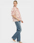 Woman wearing a floral blouse and blue jeans on a white background