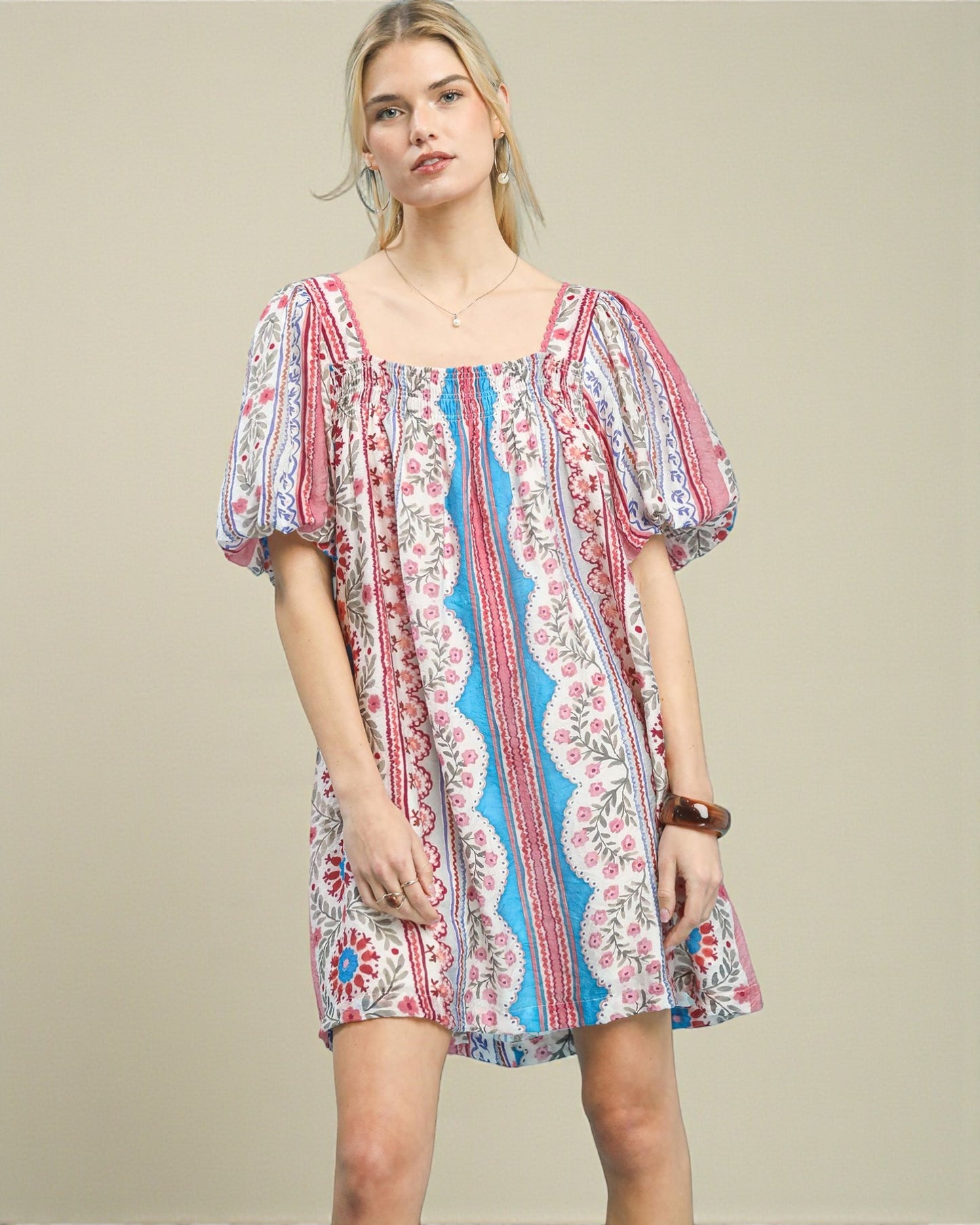 Woman wearing a colorful patterned dress on a beige background