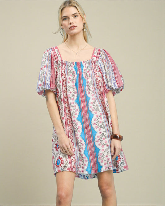 Woman wearing a colorful patterned dress on a beige background