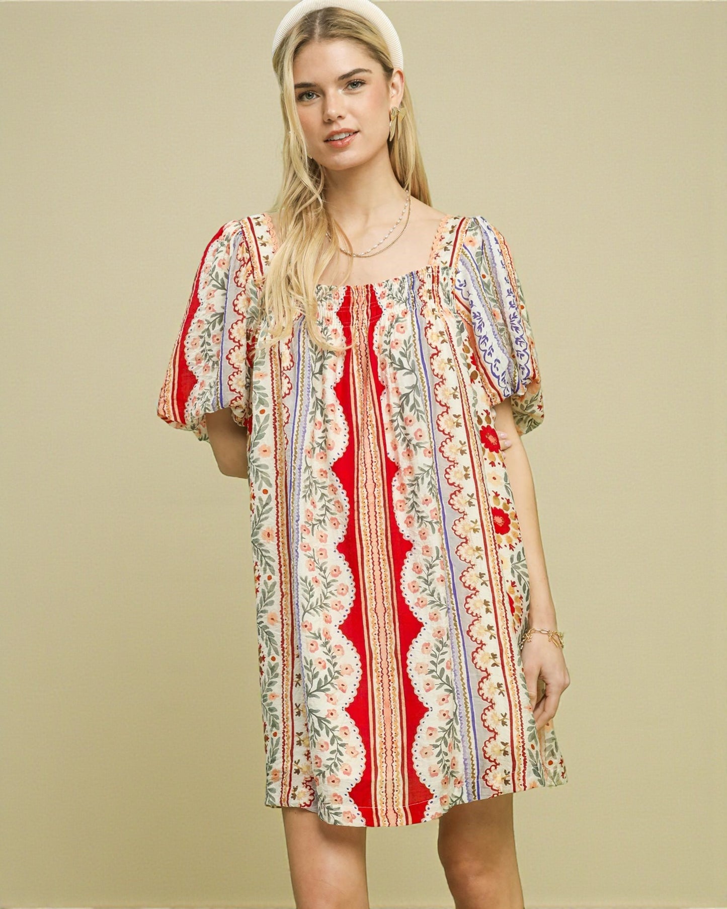 Woman wearing a colorful patterned dress on a beige background