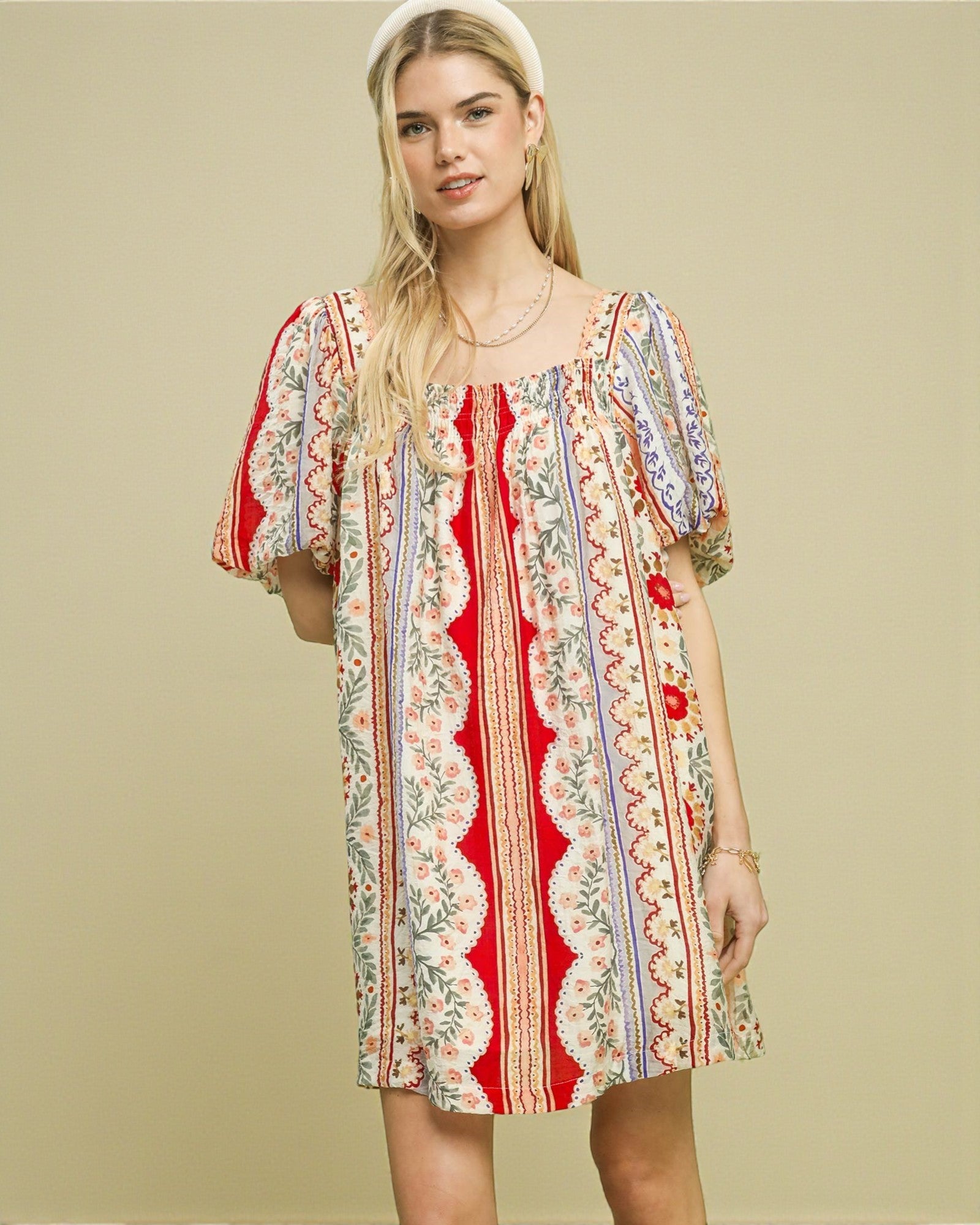 Woman wearing a colorful patterned dress on a beige background