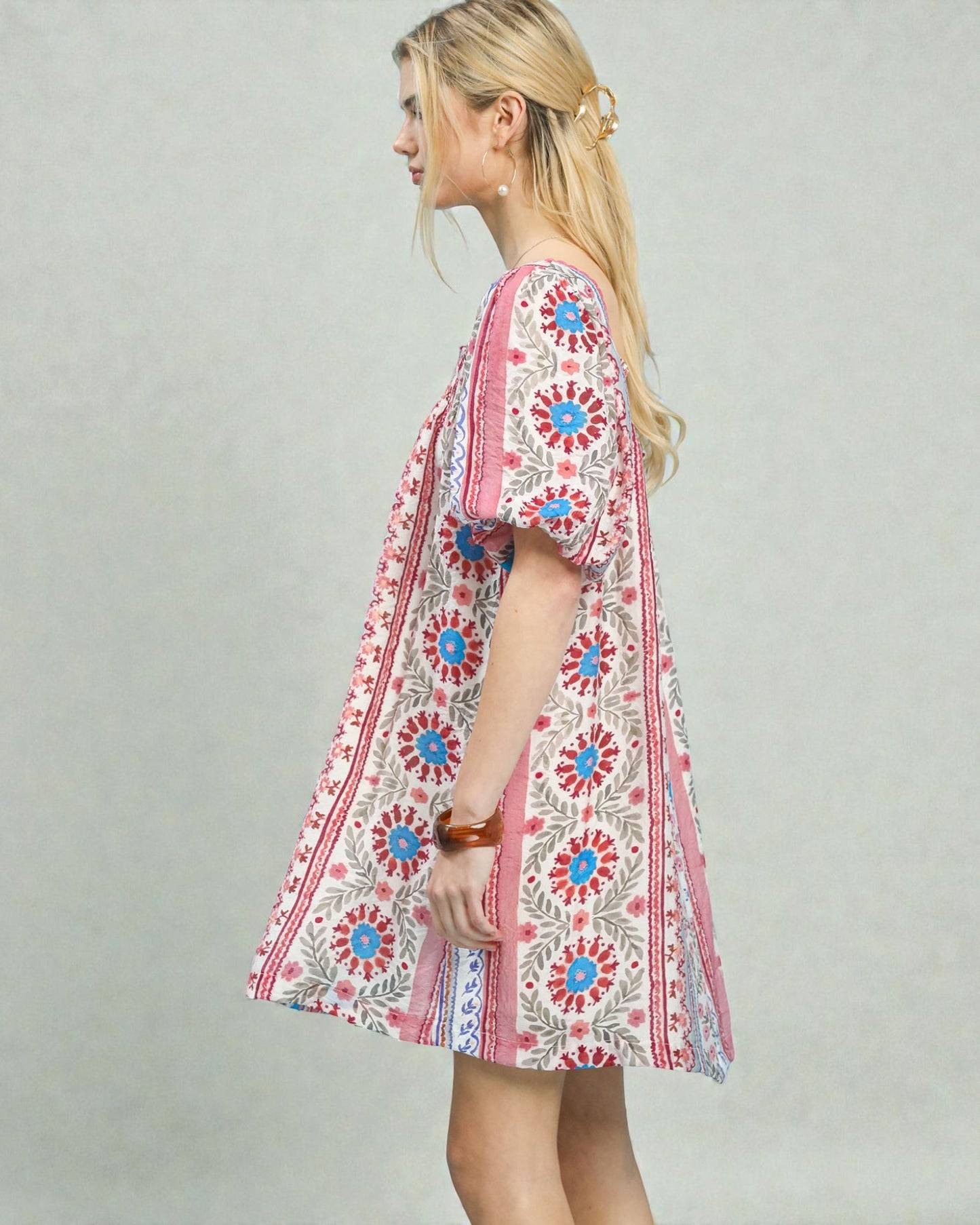 Woman wearing a colorful floral dress against a plain background