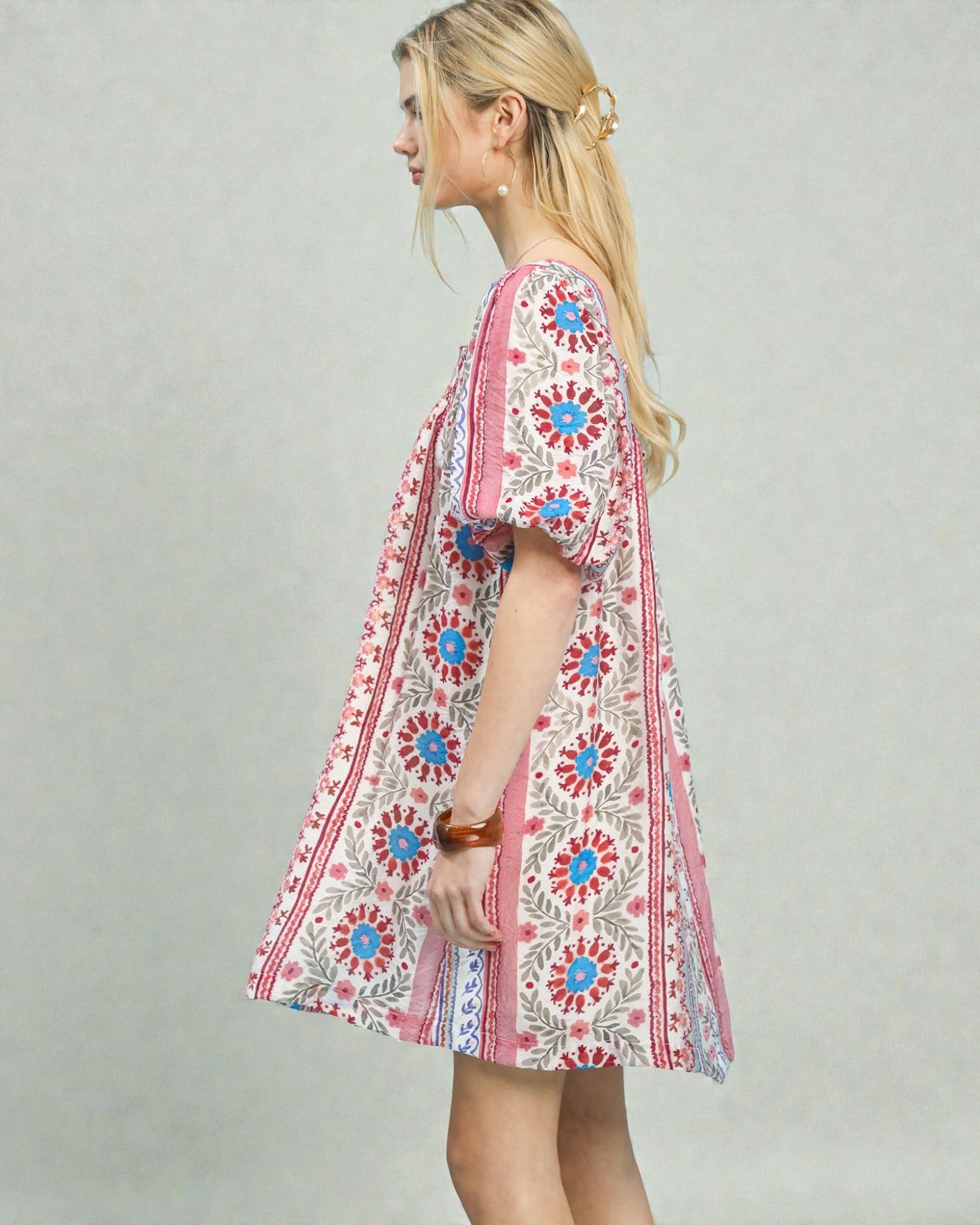 Woman wearing a colorful floral dress against a plain background