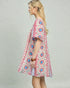 Woman wearing a colorful floral dress against a plain background
