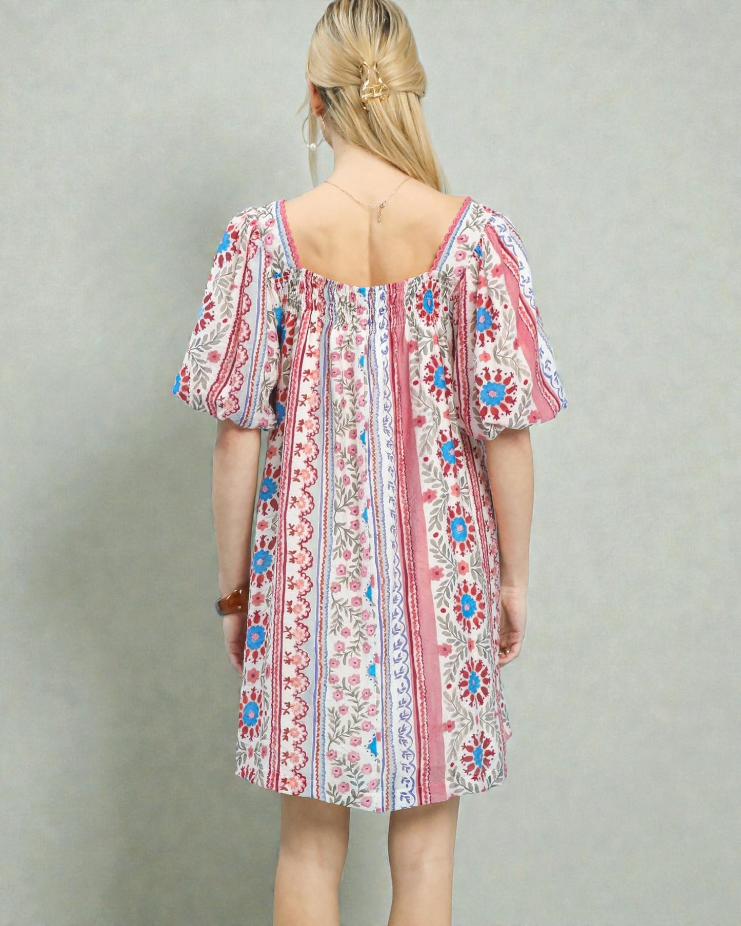 Woman wearing a colorful patterned dress against a plain background