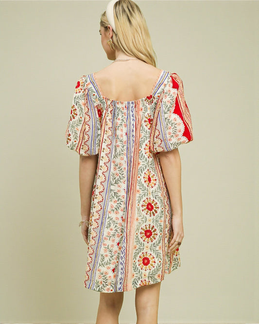 Woman wearing a floral dress with puff sleeves on a beige background