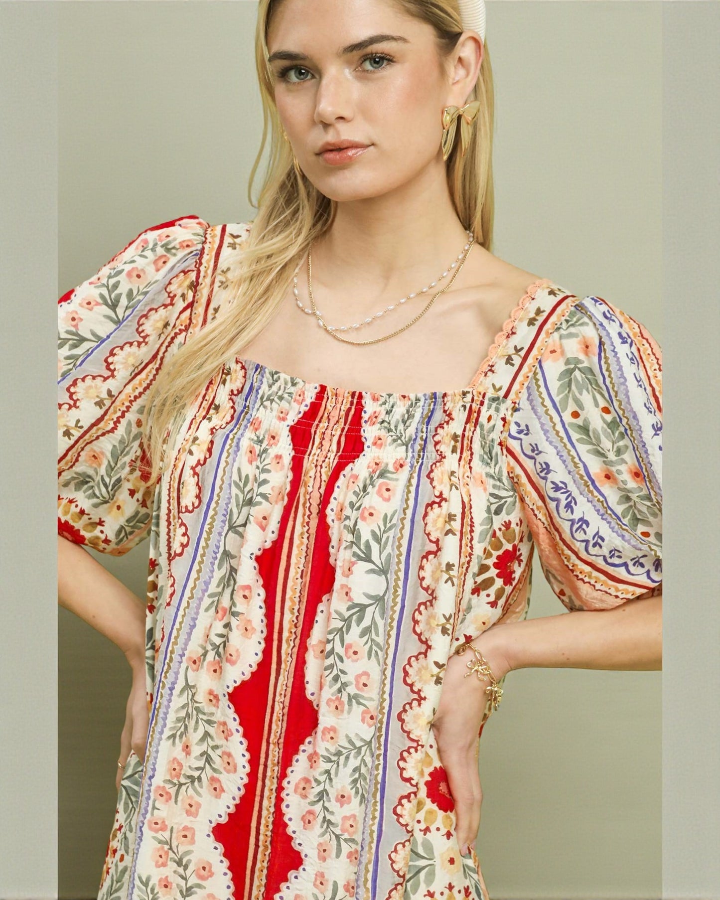 Woman wearing a colorful patterned dress with a neutral background