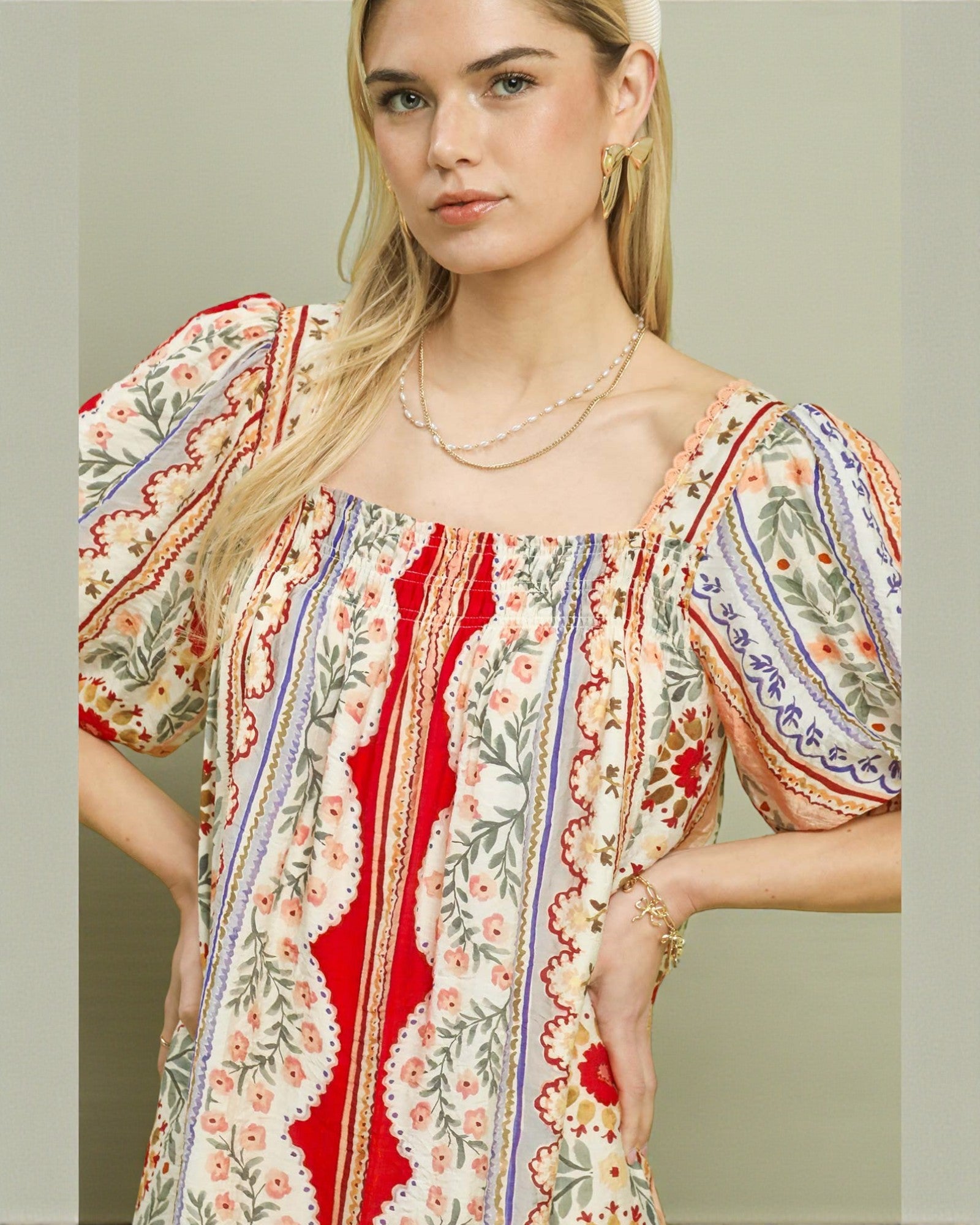 Woman wearing a colorful patterned dress with a neutral background