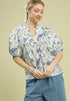 Woman wearing a floral blouse and striped pants on a beige background