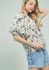 Woman wearing a floral blouse and denim shorts against a light gray background
