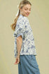 Woman wearing a floral blouse and blue pants against a beige background