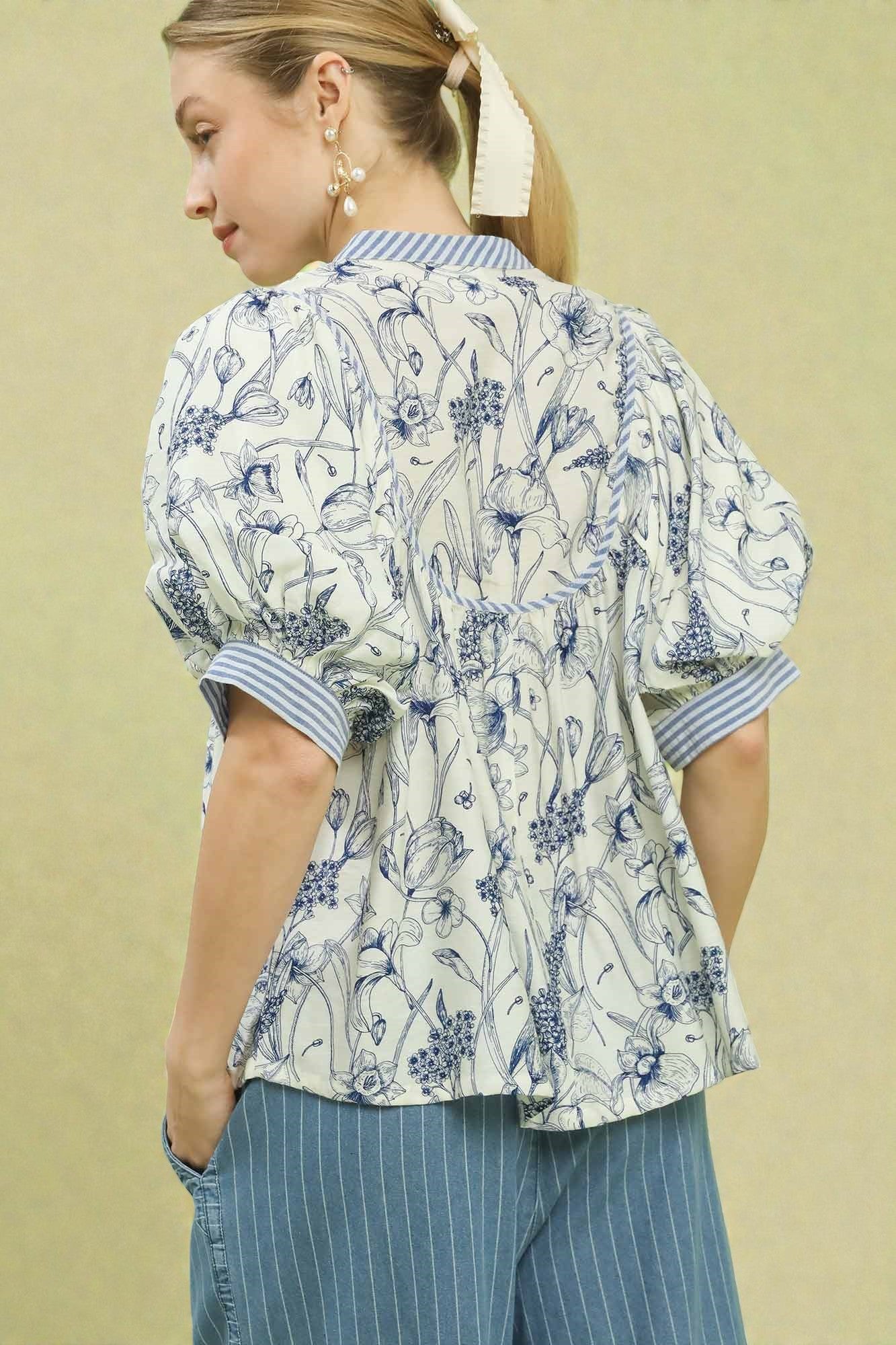 Woman wearing a floral blouse with puffed sleeves against a beige background
