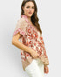 Woman wearing a floral patterned blouse on a plain background