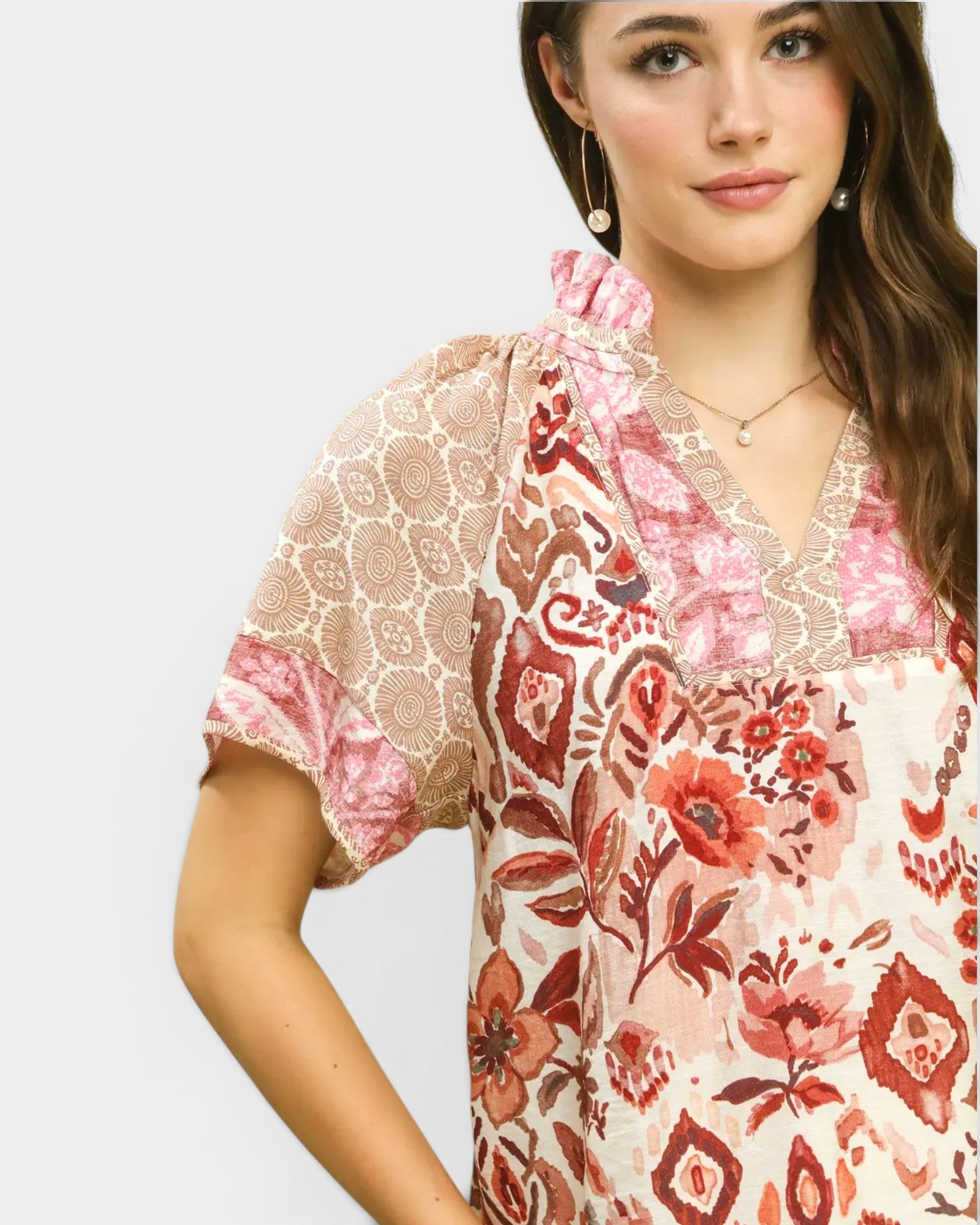 Woman wearing a floral and lace top on a plain background