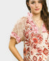 Woman wearing a floral and lace top on a plain background