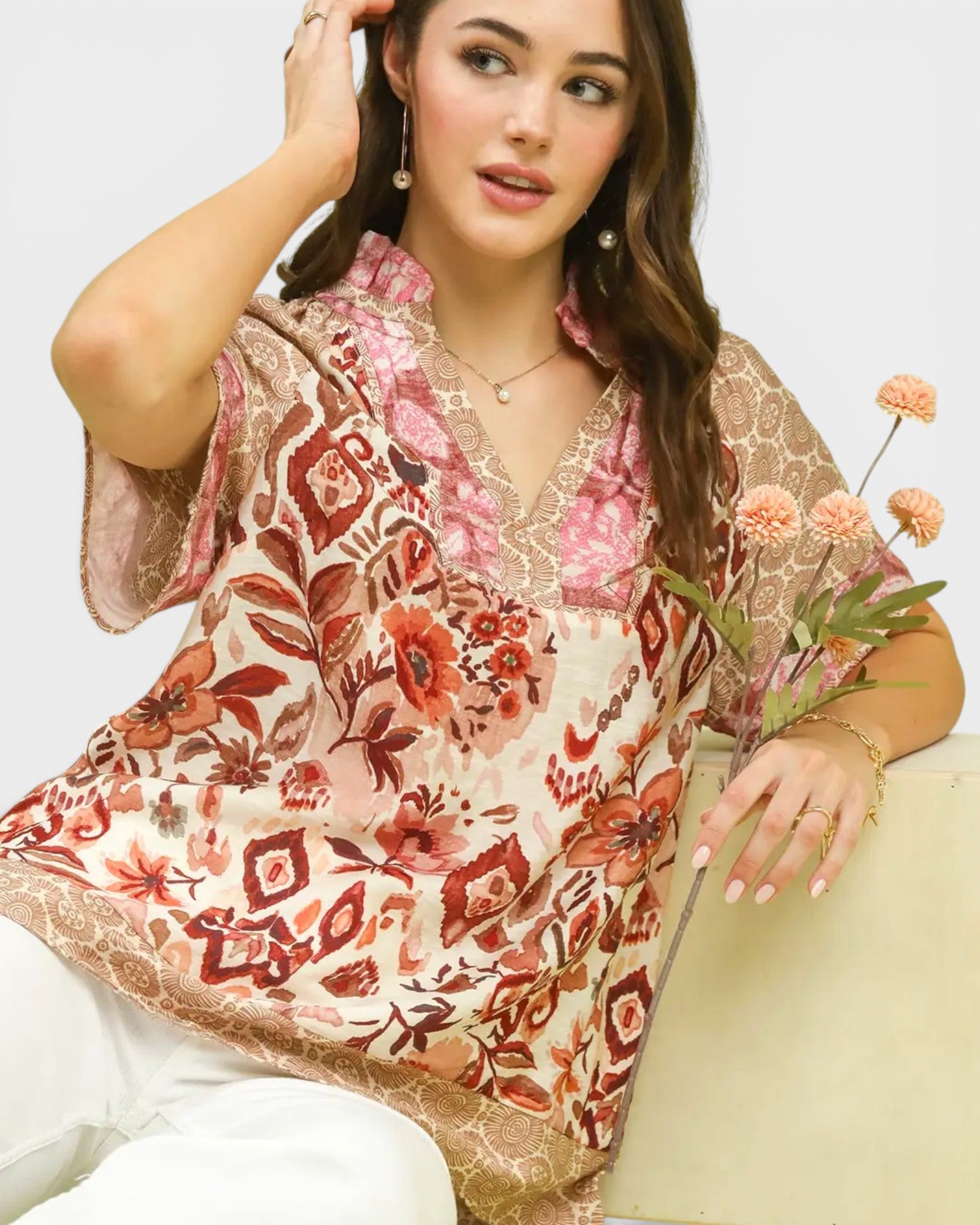 Woman wearing a floral kimono-style top holding flowers against a white background