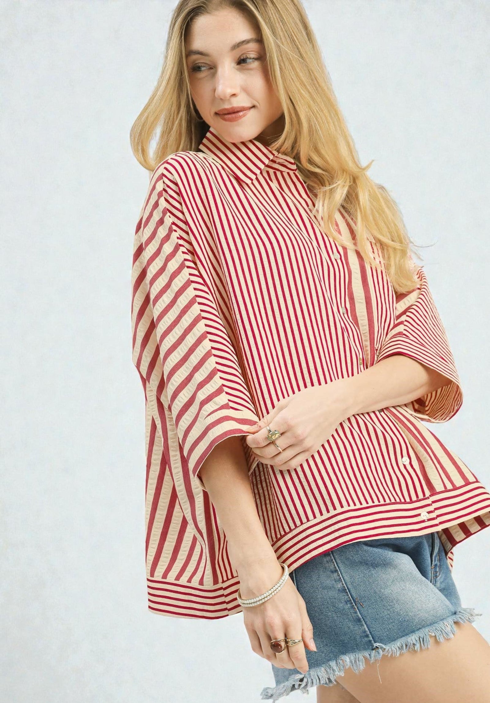 Woman wearing a red and white striped poncho on a light gray background