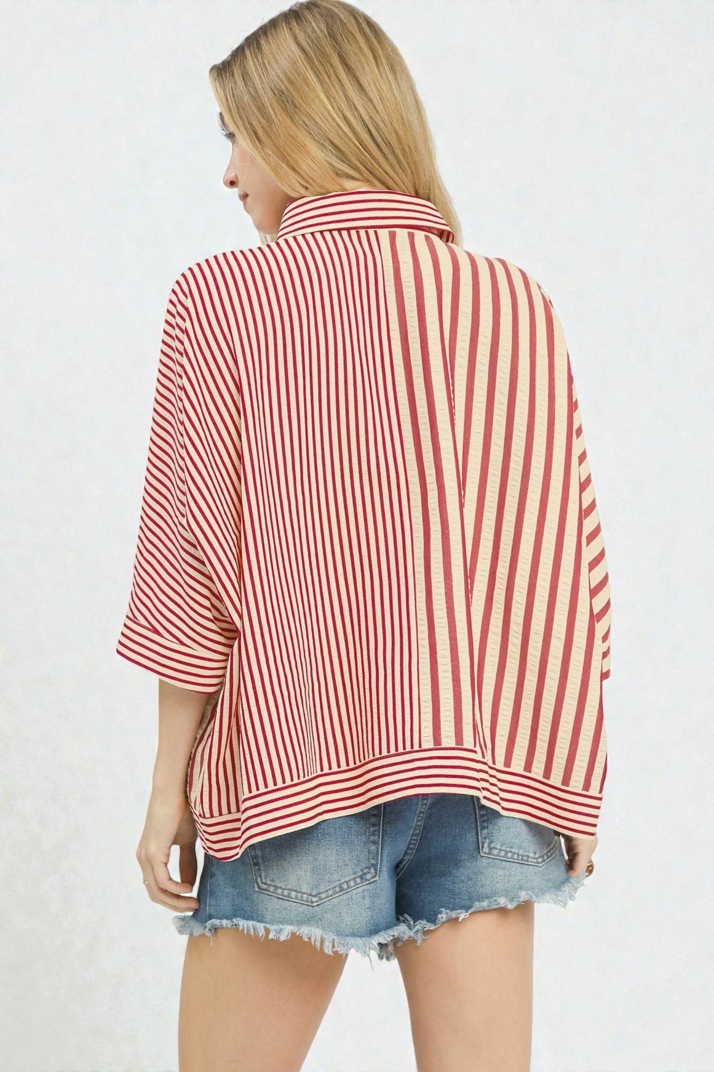 Woman wearing a red and white striped shirt with denim shorts on a light gray background