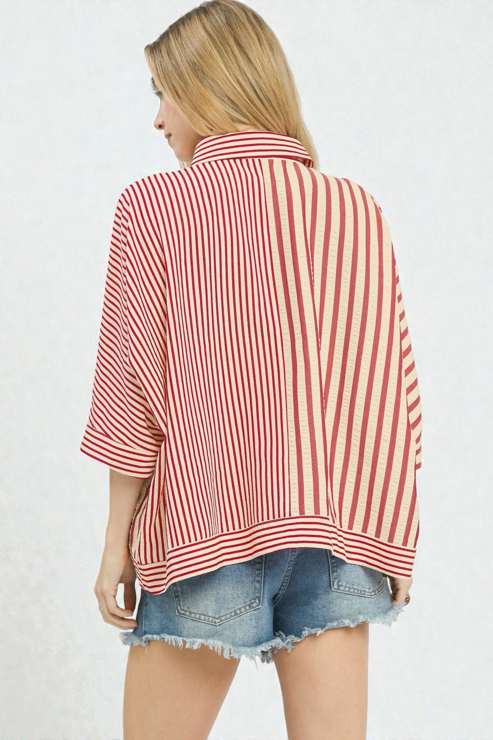 Woman wearing a red and white striped shirt with denim shorts on a light gray background