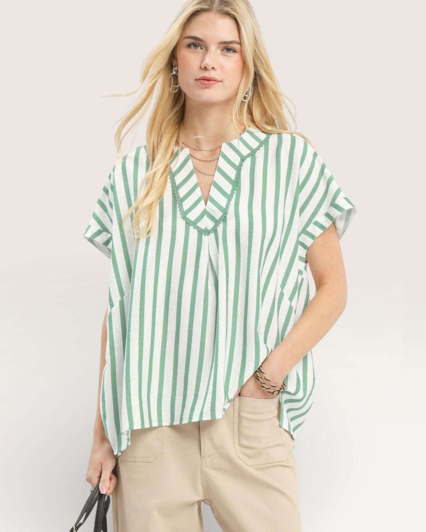 Woman wearing a green and white striped shirt against a plain background