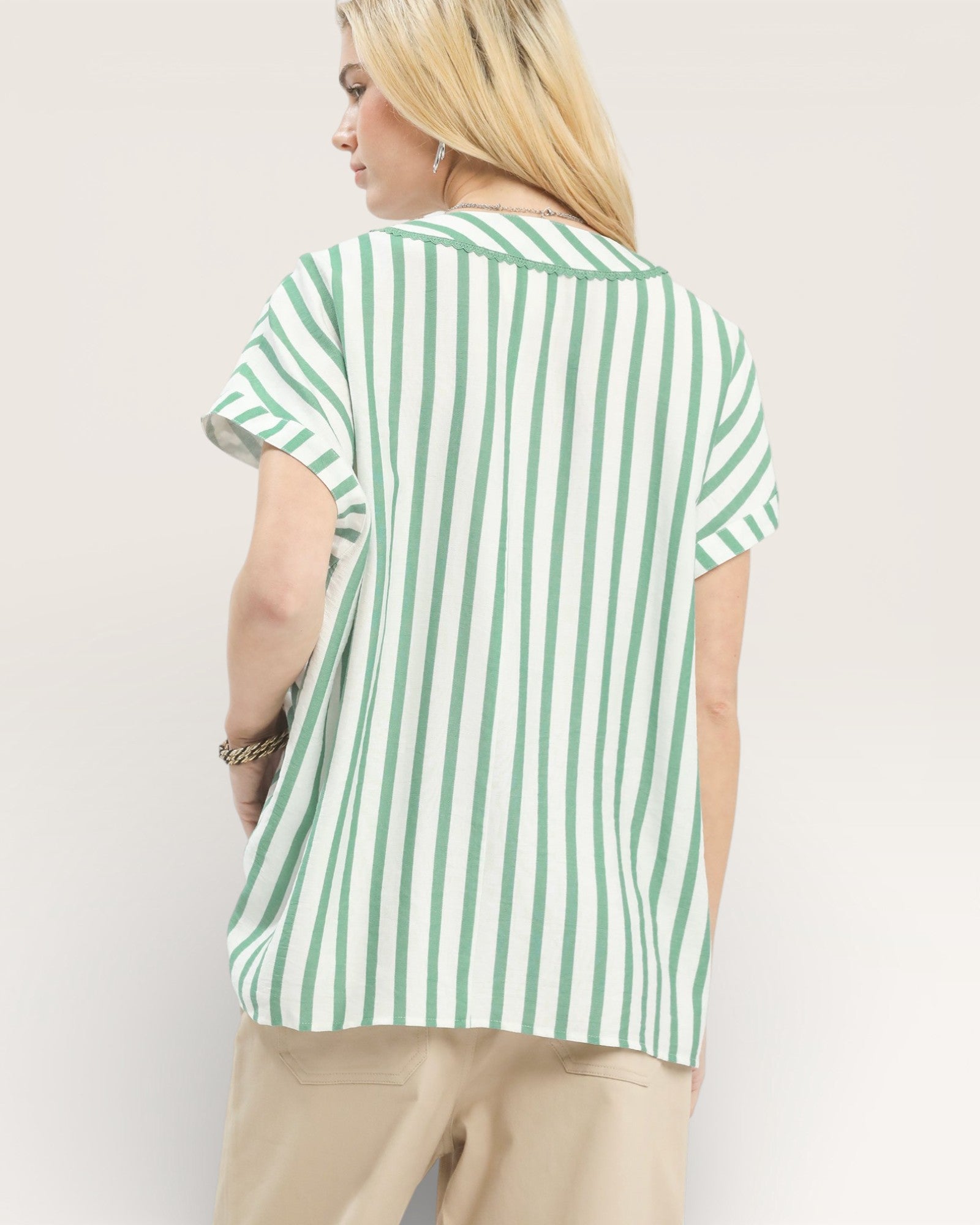 Person wearing a green and white striped shirt against a plain background