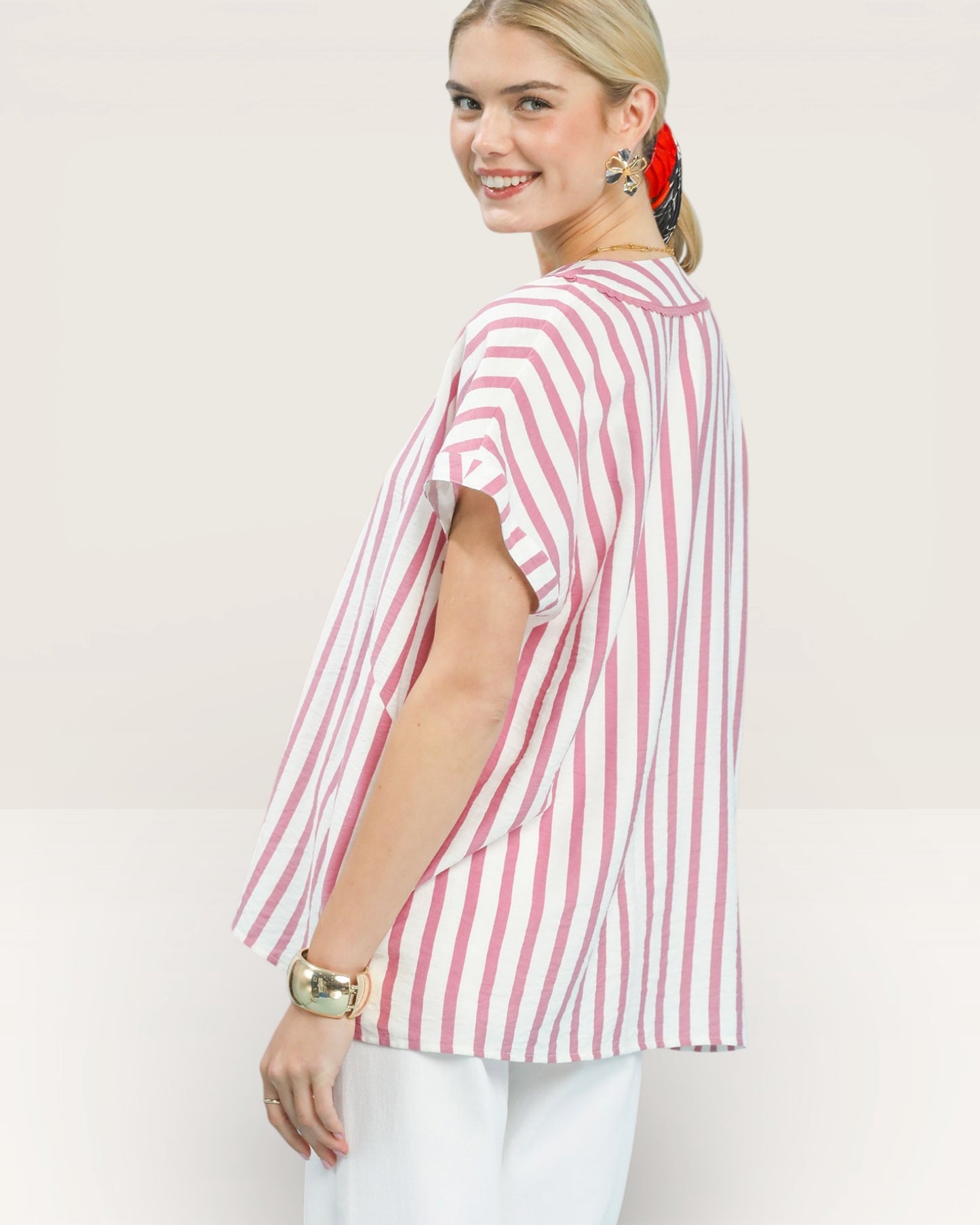 Woman wearing a pink and white striped shirt against a plain background